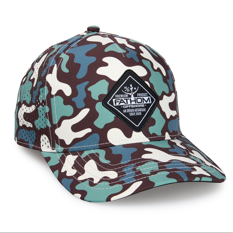 A structured baseball cap featuring a multi-color camouflage pattern in brown, teal, and off-white. It has a black diamond-shaped patch on the front with the brand name 'FATHOM OFFSHORE' and a fisherman graphic.